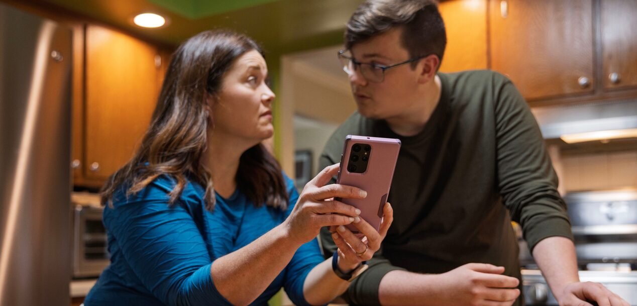 A mother showing her son something on her smartphone.