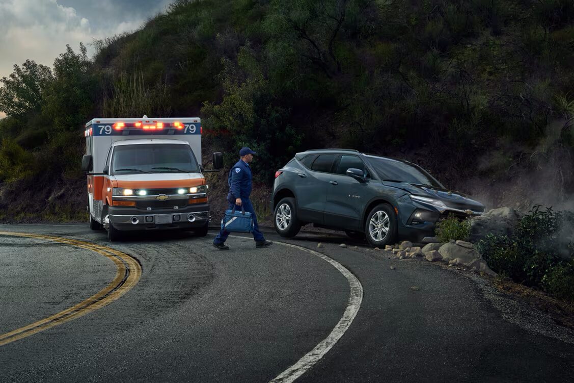 A vehicle crashed on the side of the road with an ambulance next to it.