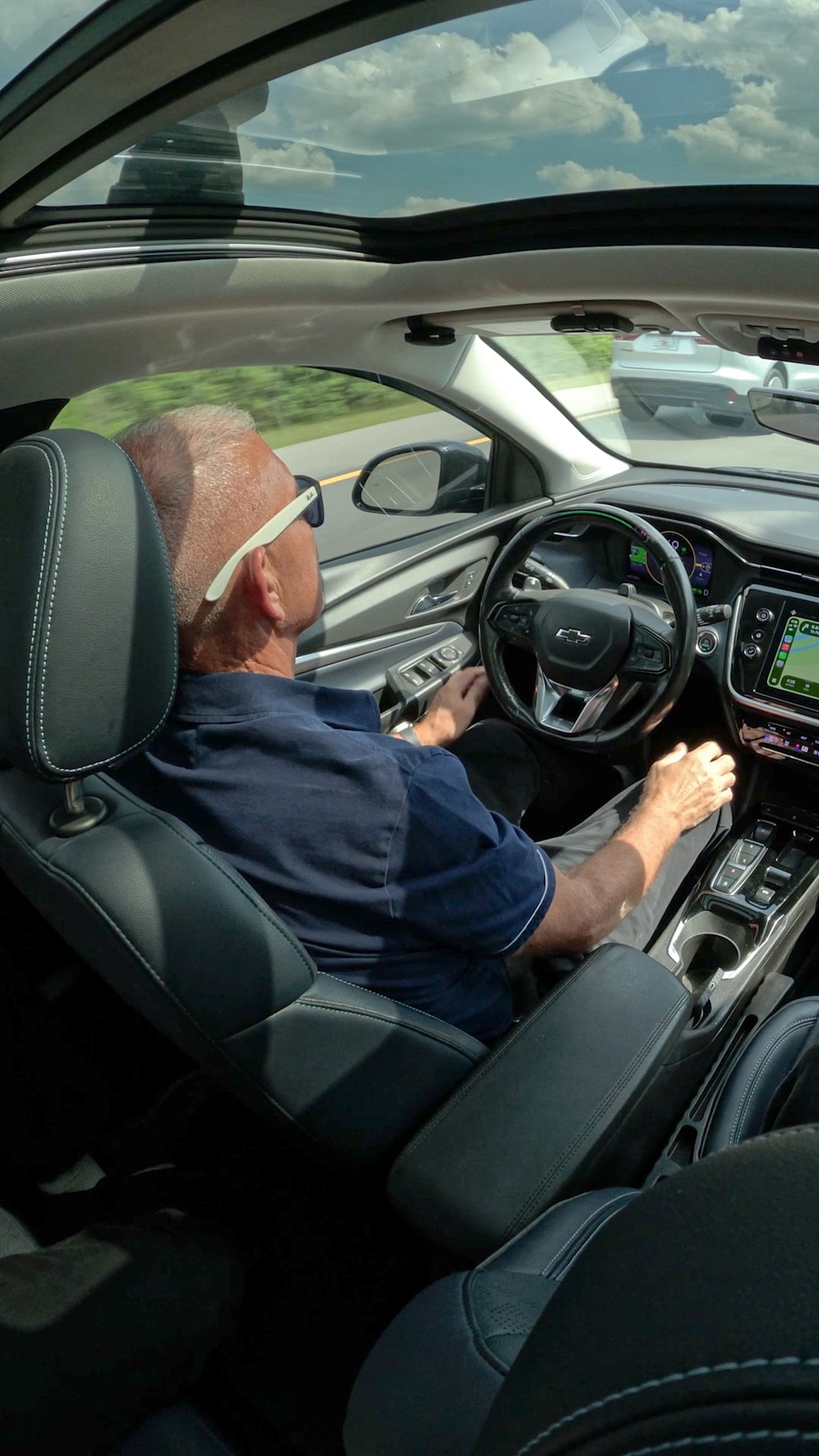 Mark P. drives his Chevrolet Bolt EUV on a highway, hands near the steering wheel, attentive to the road.