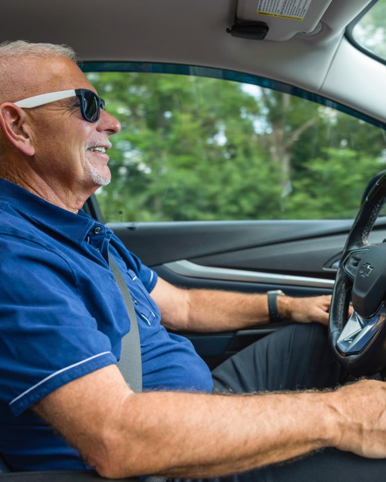 Mark P. smiles, driving his Chevrolet Bolt EUV with his hands in his lap, utilizing the Super Cruise feature.