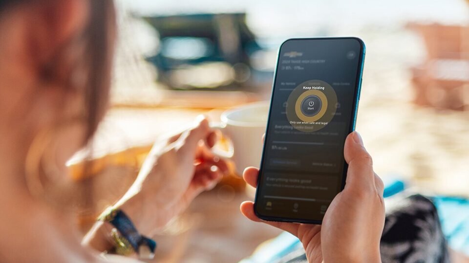 Person using a smartphone app to check vehicle status remotely.