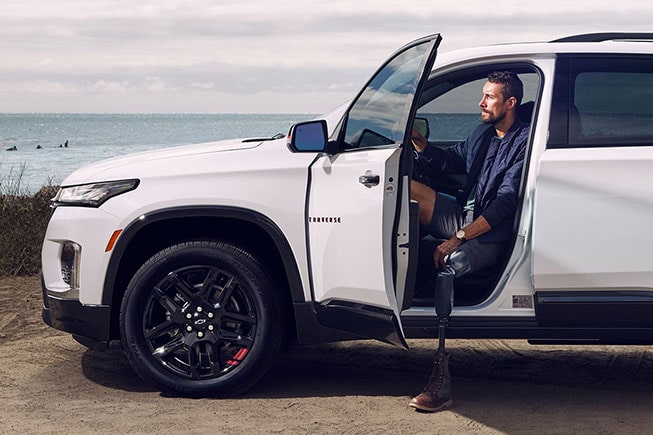 A man with a prosthetic leg stepping out of his GM vehicle at the beach