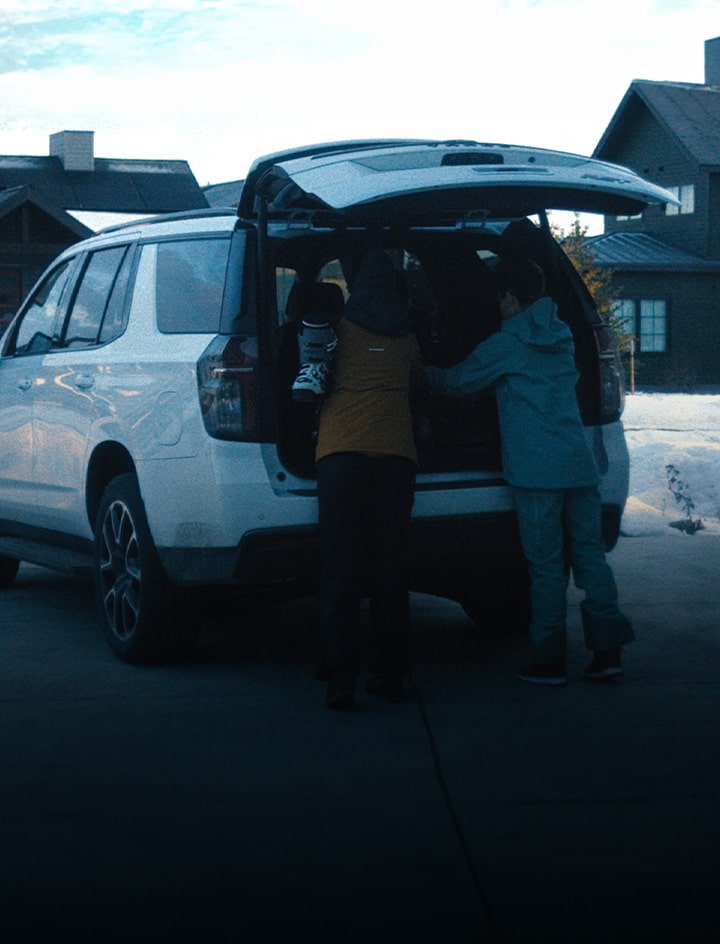 Couple loading skiing gear into the back of their GM vehicle