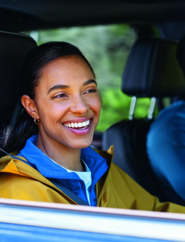 Man and woman smiling while driving in their GM vehicle