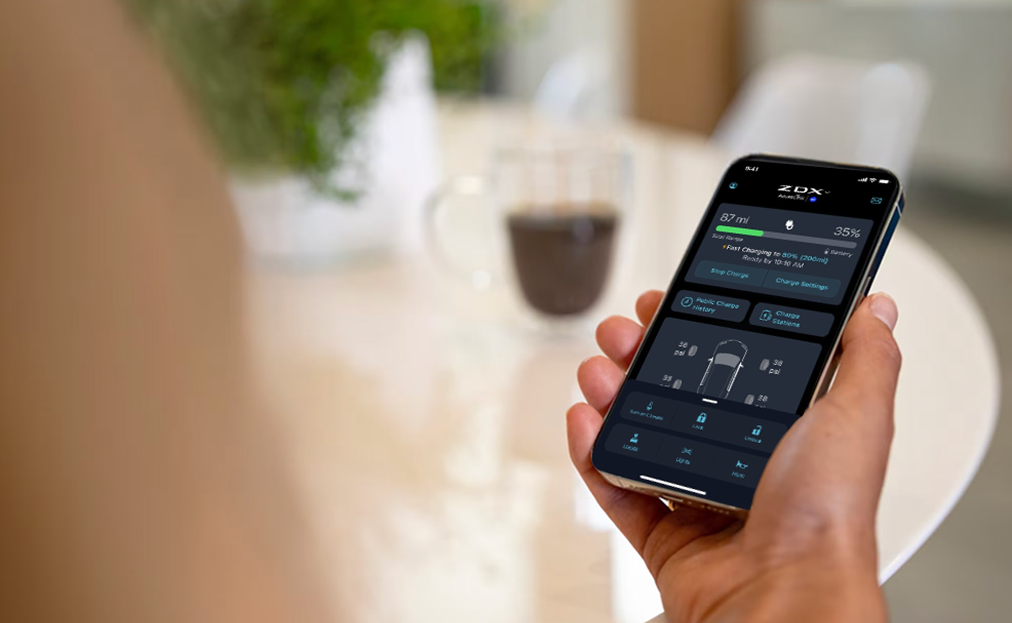 A person holds a smartphone displaying the AcuraLink app with car status and controls.
