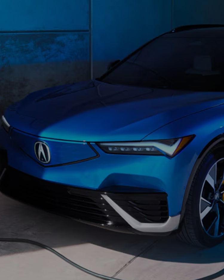 A close-up of the front of a blue electric Acura vehicle with its distinctive headlights and grille.