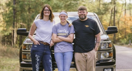 Family of Three Leaning Against Chevy Pickup Truck Smiling  