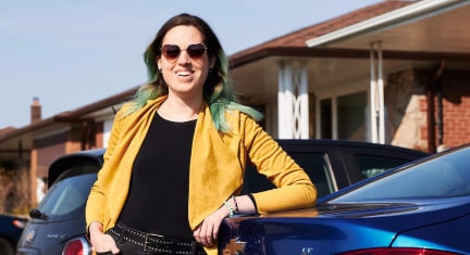Woman Standing Smiling on the Rear of her GM Car