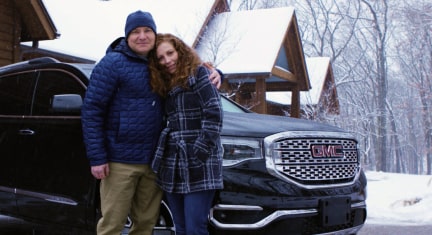Couple Stands in Front of GMC Acadia in Winter Weather