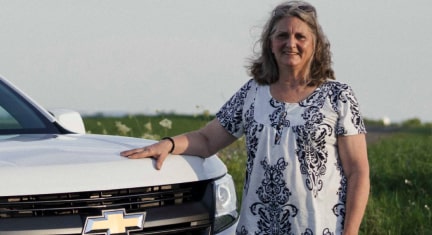 Woman Standing Next to Her Chevy Truck in a Field 