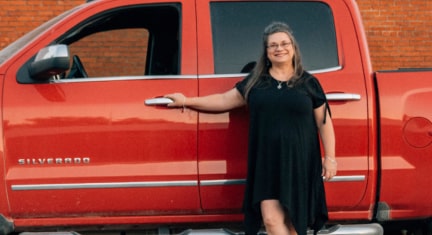 Woman Leaning on the Driver's Side of a GM Truck