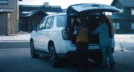 Couple loading skiing gear into the back of their GM vehicle