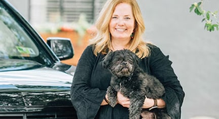 Woman With a Black Dog Standing in Front of her Chevy SUV