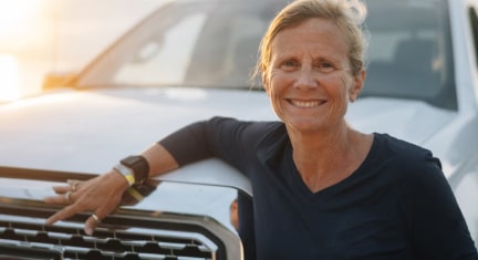 Sondi Leans on the Front of her GMC Truck While Looking at the Camera