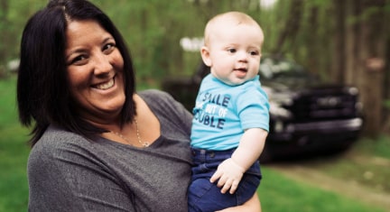 Woman holds baby with GM truck in background