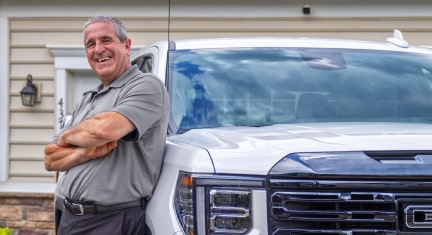 Marco C. leaning on his GMC Sierra truck that is parked in his driveway