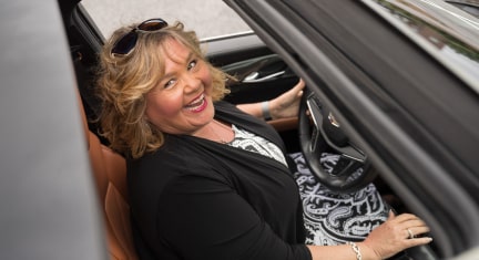 OnStar member Barbara Wrench smiling at the camera through her Cadillac sunroof