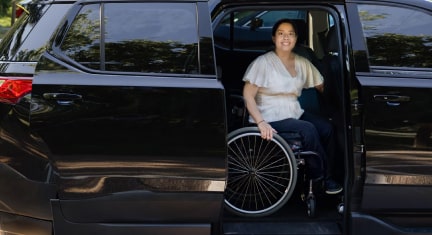 A Woman in a Wheelchair Wearing White Smiling at the Camera 
