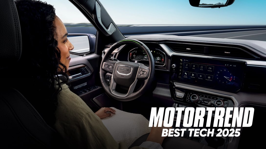 A backseat view of a woman sitting in the driver's seat with the text overlay 'MOTORTREND BEST TECH 2025'