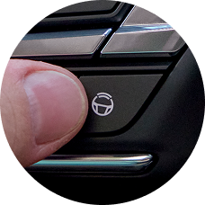 A closeup of a finger pressing the Adaptive Cruise Control button.