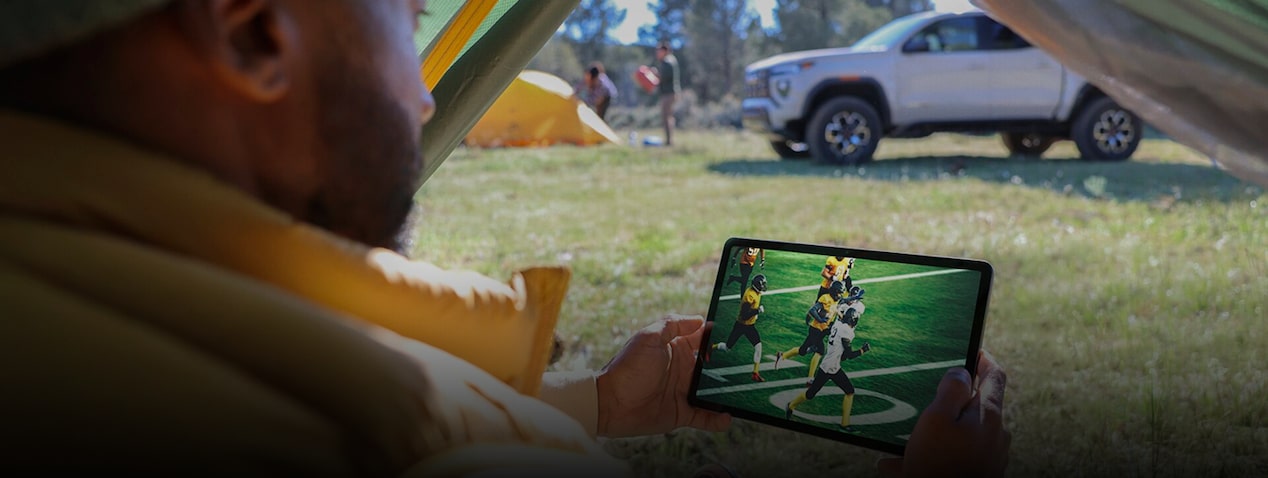 Streaming live sports on a tablet at a campsite using connected vehicle technology and Wi‑Fi hotspot access.