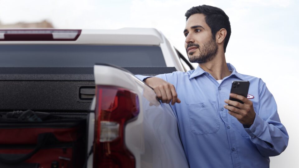 Man Holding Phone Leaning Against Truck