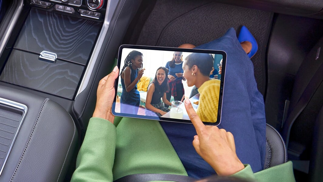 A woman in the passenger seat holding a tablet.