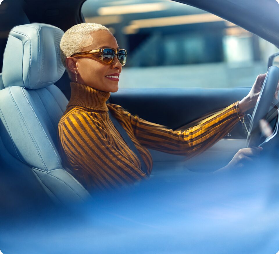 A woman driving a vehicle, highlighting the connected vehicle technology experience with OnStar.