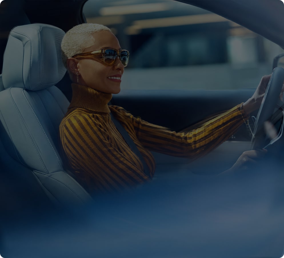 A woman driving a vehicle, highlighting the connected vehicle technology experience with OnStar.