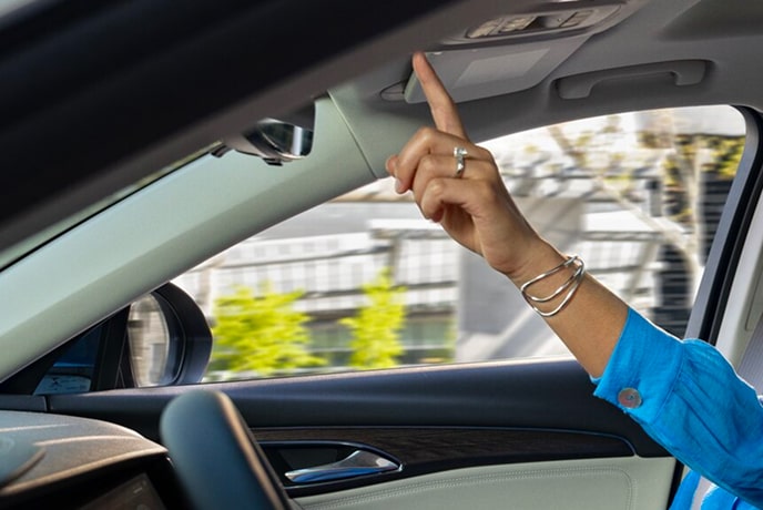 A close up of a woman's arm pressing a button on the roof of her vehicle