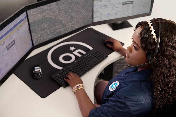 A bird's eye view of a female OnStar employee with her headset on and her hands on her keyboard and mouse.