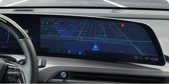 A car's wide digital dashboard screen shows a vibrant, detailed Google Maps navigation view.