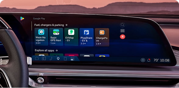 A car's wide digital dashboard screen displays the Google Play store interface with various app icons.