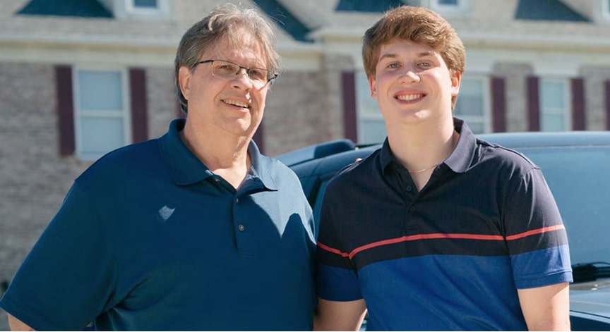Father and Son Standing Side by Side in Driveway Smiling