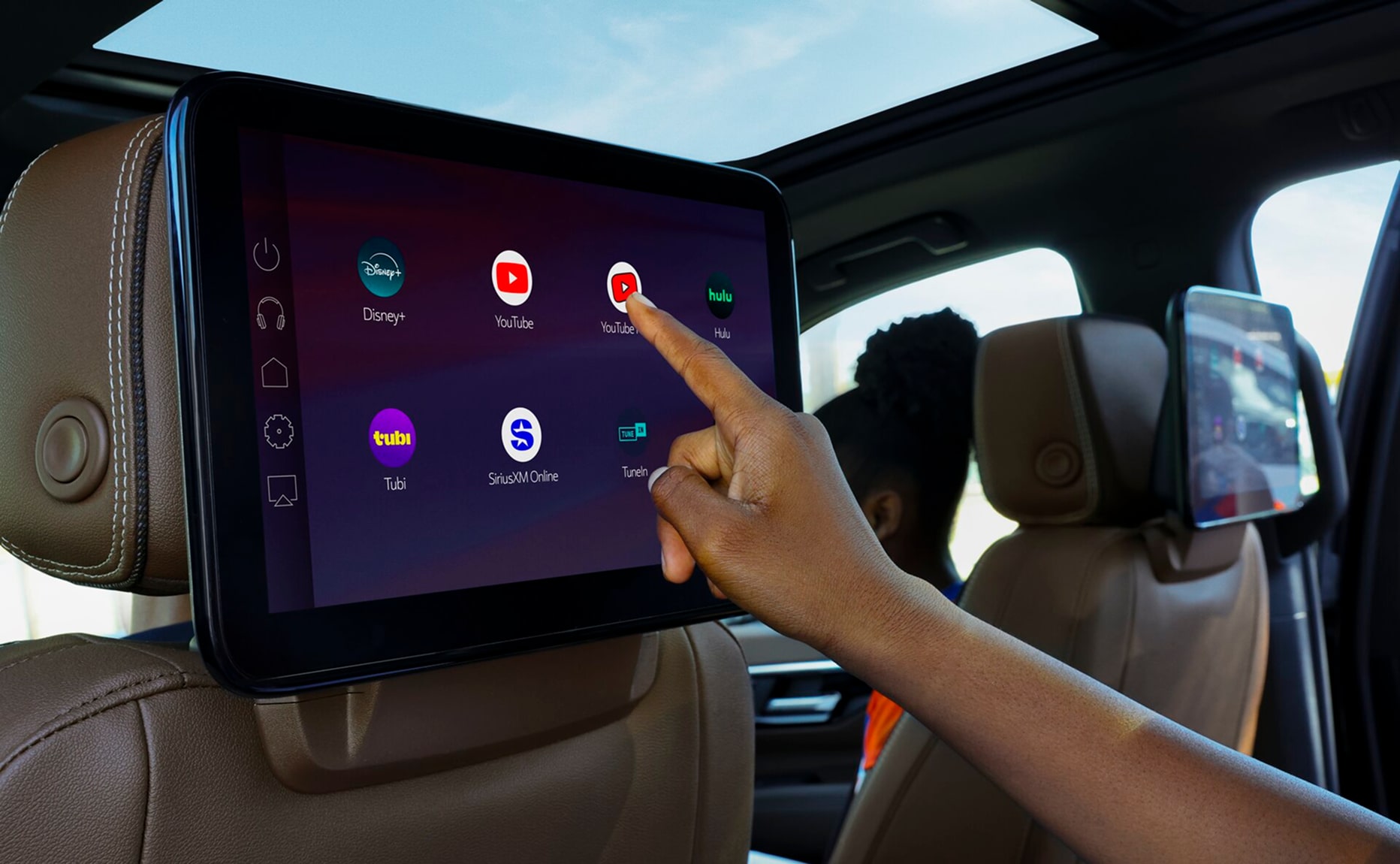 A passenger uses a rear-seat entertainment screen in an OnStar-enabled vehicle to access streaming apps including YouTube, Disney+, Hulu, Tubi, SiriusXM and TuneIn.