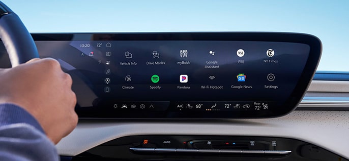 A car's wide infotainment screen displays various app icons including Spotify and Google Asistant.
