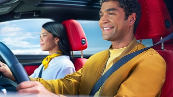 A Man Smiling While in the Driver's Seat and a Woman Sitting in the Front Passenger Seat