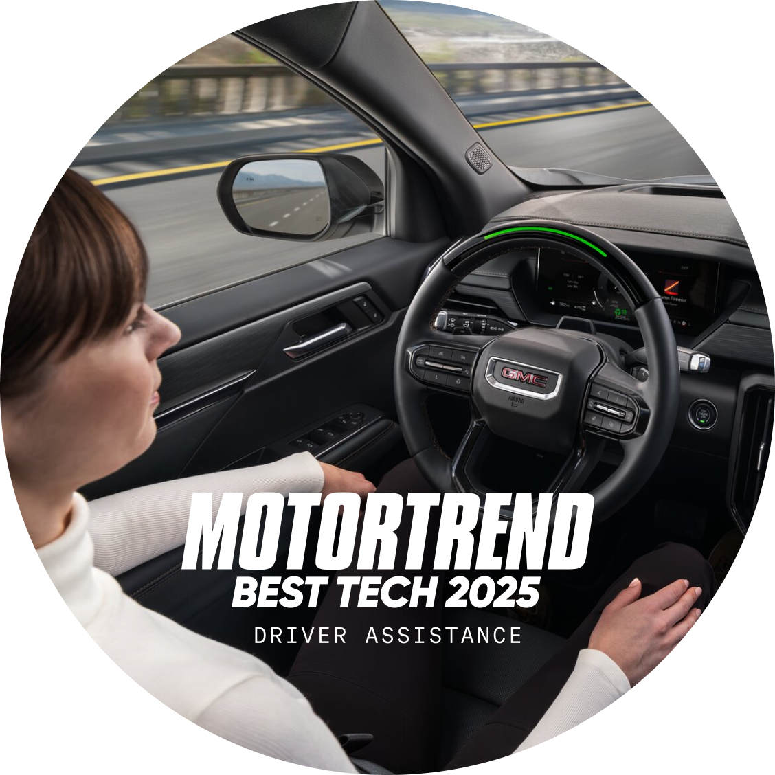 A woman is driving a vehicle with the GMC logo on the steering wheel and the text "motortrend best tech 2025 driver assistance" overlaid in a circular profile image.