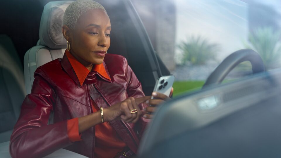A woman sitting in her car using her smartphone
