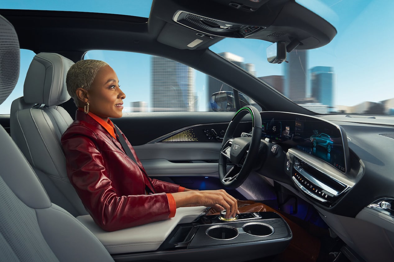 A side view of a woman driving a vehicle with her arm resting on the middle console