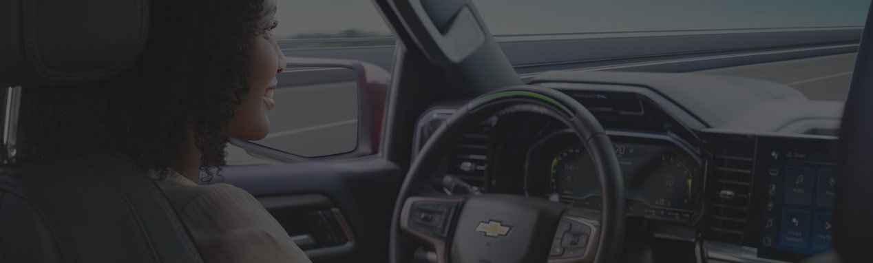 Side view of a woman in the driver seat of a Chevy vehicle.