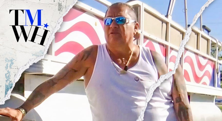A man posing for photo wearing sunglasses and a white T-shirt on a sunny day next to the text overlay of "Tell Me What Happened".  
