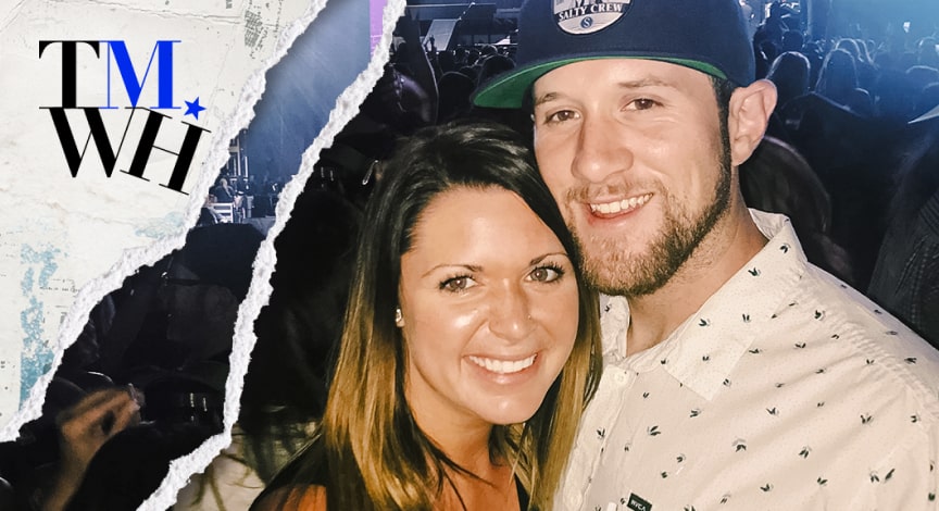 A couple smiling with a group people behind them.