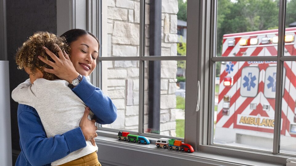 Parent Holds Child As Ambulance Pulls up to the House