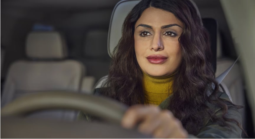 A calm woman with long dark hair driving a car at night, knowing she has OnStar roadside asistance for any emergency.
