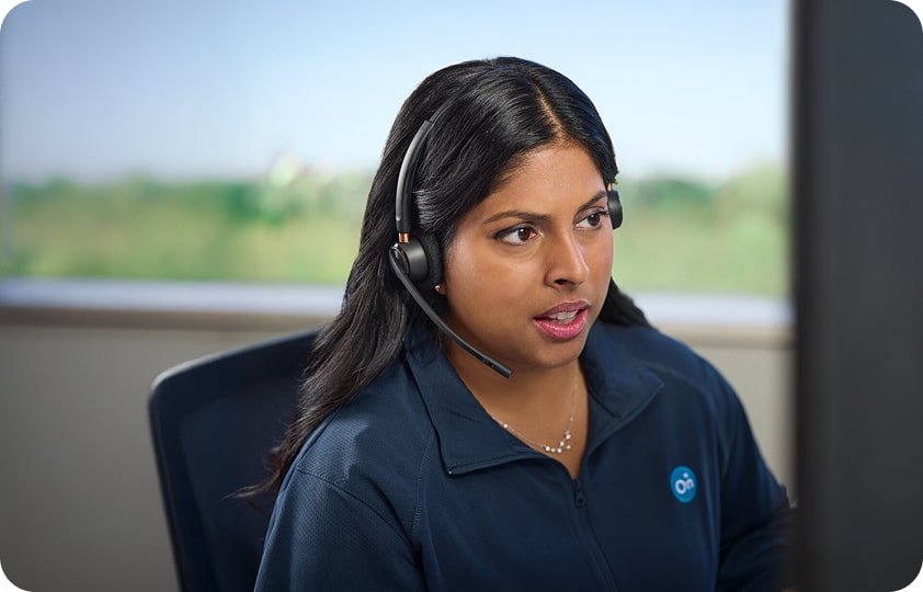 A young woman of the stolen vehicle OnStar assistance team, wearing a headset and a blue OnStar polo shirt, looking intently at a computer screen.