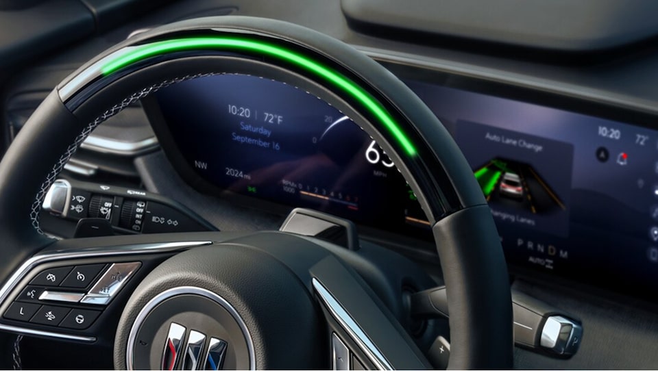 A Buick steering wheel with a bright green light bar at the top, indicating that Super Cruise Hands Free Driving is active, and a digital dashboard displaying navigation details.