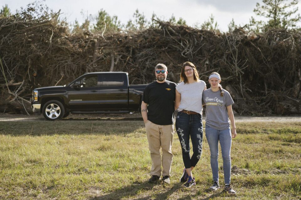 Family Embraces in a Field In Front of a GM Truck