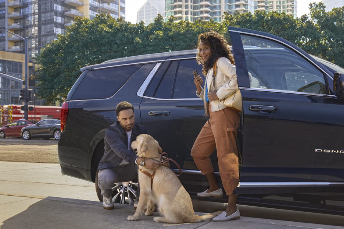 Couple Standing Next to GM Vehicle with Their Dog
