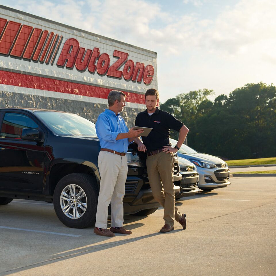 Two Men Looking at a Tablet in Front of AutoZone